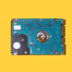 ATA SATA portable hard drive with the circuitry visible on a yellow background. Concept of computing, hardware, hard drive, storage, data, PC, assembly, technician and engineer.