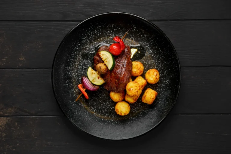 Top view of grilled beef with vegetables and potato balls on a plate