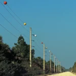 Colorful Visibility Marker Balls on power lines along a gravel road in Florida